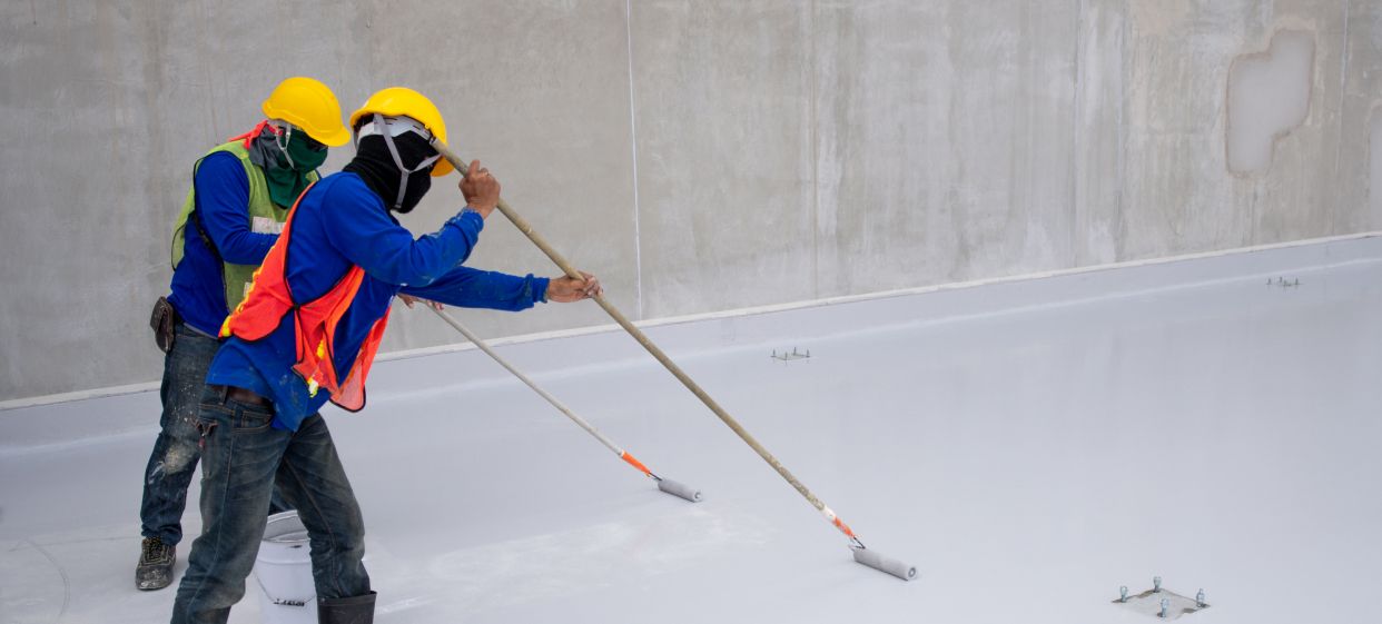 Worker applying PU foam waterproofing system in Qatar
